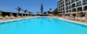 a large swimming pool with chairs and a building at Ocean Front Cura Beach in Playa del Cura +15 photos