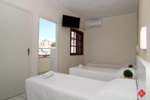 two beds in a room with a tv on the wall at Hotel Elevado in Porto Alegre