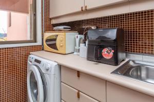 a kitchen counter with a washing machine and a microwave at Lisbon at Home in Lisbon