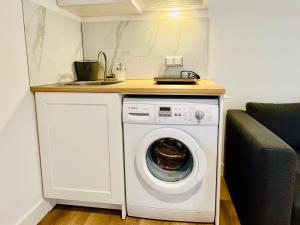 a kitchen with a washing machine and a sink at Stylish private-entrance studio with bath and shower near Nijmegen Centre and Arnhem Zuid in Nijmegen