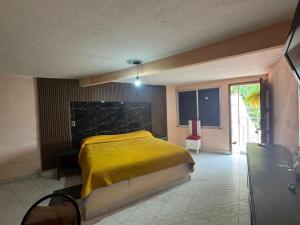 a bedroom with a bed with a yellow blanket on it at Hotel Acambay in Acambay