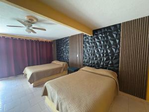 a hotel room with two beds and a ceiling fan at Hotel Acambay in Acambay