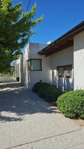 a white building with a tree next to a sidewalk at Casa Clara in Rufino