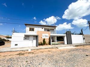 a white house on the side of a road at Eficiência - Casa Recanto dos Ventos - Casa grande para lazer entre família e amigos in Camocim