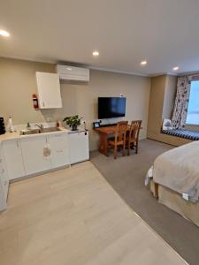 a bedroom with a bed and a sink and a kitchen at Orchards Retreat in Paraparaumu Beach