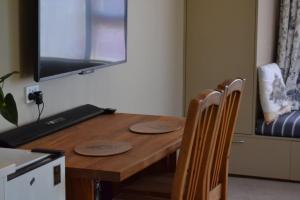 a wooden table with two chairs and a television on the wall at Orchards Retreat in Paraparaumu Beach +3 photos