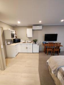 a kitchen with white cabinets and a table and a television at Orchards Retreat in Paraparaumu Beach