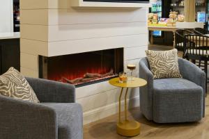 two chairs and a fireplace in a store at Tiller House, Laguna Hills, a Tribute Portfolio Hotel in Laguna Hills