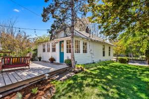 a white house with a porch and a wooden deck at Bluebird Day - Jefferson Cottage in Bend