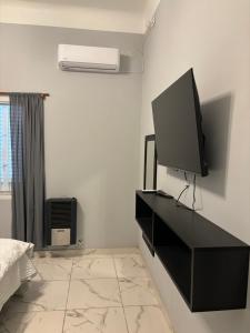 a bedroom with a television on a black dresser at Hospedaje Adha Chivilcoy III in Chivilcoy