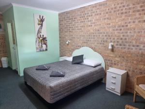 a bedroom with a bed and a brick wall at Tiaro Motor Inn in Tiaro