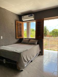 a bedroom with a bed and a window at Pousada encantos de morro branco in Beberibe