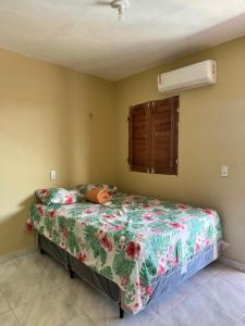 a bedroom with a bed with a floral comforter at Pousada encantos de morro branco in Beberibe