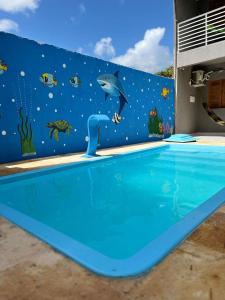 a mural of a dolphin on the side of a swimming pool at Pousada encantos de morro branco in Beberibe