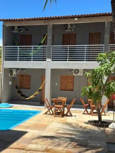 a resort with a hammock and a table and chairs at Pousada encantos de morro branco in Beberibe