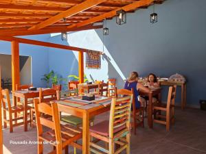 two people sitting at tables in a restaurant at Pousada Aroma de Café em Socorro-SP in Socorro