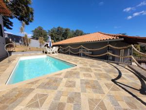 a swimming pool with a patio and a house at Chacara Recanto Mirella in Socorro
