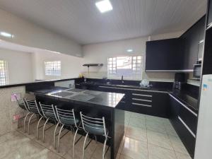a kitchen with a black counter and some chairs at Chacara Recanto Mirella in Socorro