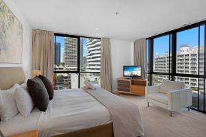 a bedroom with a large bed and a tv and windows at Aria Apartments in Gold Coast +175 photos