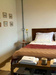a bedroom with a bed with a table next to it at Chalé das Flores - Refúgio com clima de chácara no Centro de Gonçalves in Gonçalves