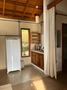 a kitchen with a white refrigerator and a window at Chalé das Flores - Refúgio com clima de chácara no Centro de Gonçalves in Gonçalves