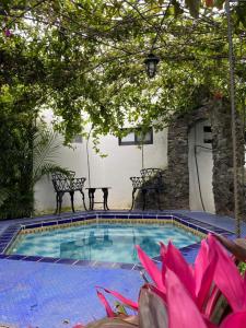 a swimming pool with two benches next to a building at Posada Los Alcatraces in Atlixco