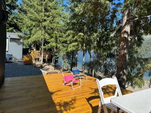 two chairs and a table on a wooden deck at Cabaña Sobre Playa Lago Gutiérrez 2 in San Carlos de Bariloche