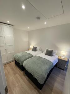 two beds in a white room with two lamps on tables at Howth Village Cottage in Howth