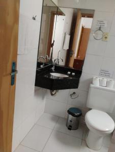 ein Badezimmer mit Toilette, Waschbecken und Spiegel in der Unterkunft Osório Hotel in Osório