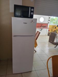 a white refrigerator with a microwave on top of it at La Parenthèse Verte à ducos in Ducos