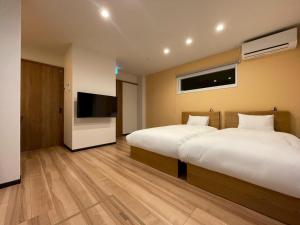 a hotel room with two beds and a flat screen tv at Casa Kokoro Hakuba in Hakuba