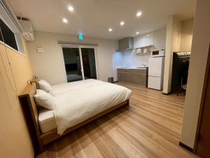 a bedroom with a white bed and a kitchen at Casa Kokoro Hakuba in Hakuba