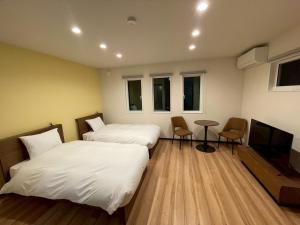a room with two beds and a tv and a table at Casa Kokoro Hakuba in Hakuba