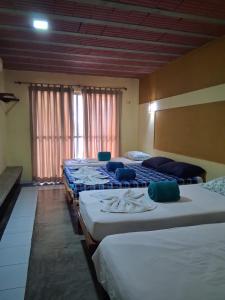 a row of beds in a room with windows at Pousada Nosso Recanto Camocim in Camocim