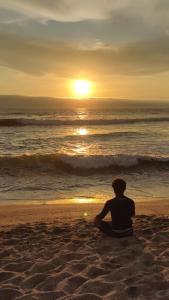 a person sitting on the beach watching the sunset at La Palmera Apartment in San Bartolo