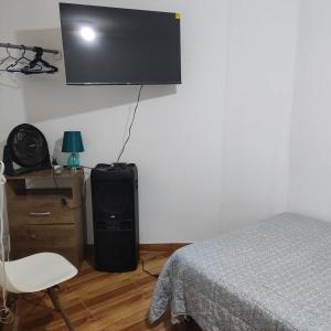 a bedroom with a bed and a tv on the wall at La Palmera Apartment in San Bartolo