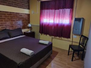 a bedroom with a bed and a chair and a window at Lo de Norma in Neuquén