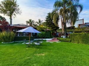 a lawn with chairs and an umbrella in a yard at Posada Los Alcatraces in Atlixco