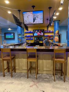 a man sitting at a bar with three chairs at Hotel Royal Blue & Golf Cart Rental in San Pedro