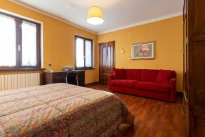 a bedroom with a bed and a red couch at B&B Cascina Baraggione in Granozzo con Monticello