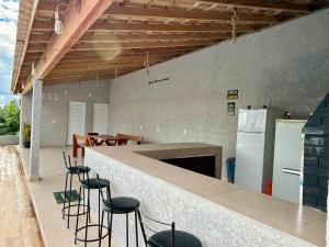 a kitchen with a counter with chairs and a refrigerator at Chalés Sonho Meu in Munhoz
