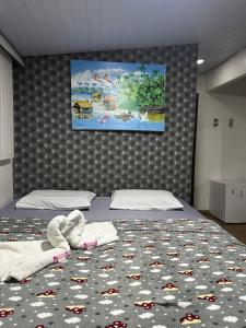 a bedroom with two beds and a painting on the wall at Hotel Araras in Manaus