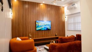 a living room with two chairs and a tv on a wall at Golden Appart in Godomey