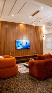 a living room with orange chairs and a flat screen tv at Golden Appart in Godomey