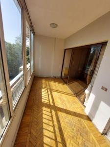 an empty room with a wooden floor and large windows at Cozy Queen bed room in zamalek with garden view and balcony in Cairo