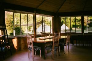 a dining room with a table and chairs and windows at Amanecer Glamping in llifen