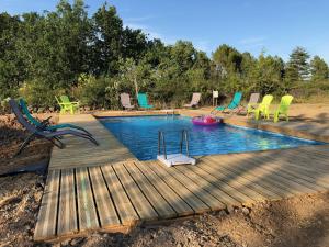 a swimming pool with chairs and a wooden deck at Hamlet de moment Ardeche com in Lablachère