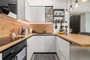 a kitchen with white cabinets and a wooden counter top at NOVA SPA - Sauna Suite for Two in Rijeka