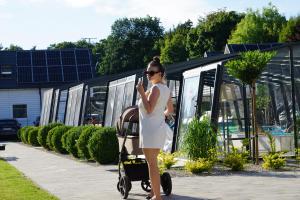 a woman in a white dress walking with a baby carriage at Domki OLIVIA in Darlowko