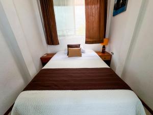 a bed in a small room with a window at Maytenus Galapagos in Puerto Ayora